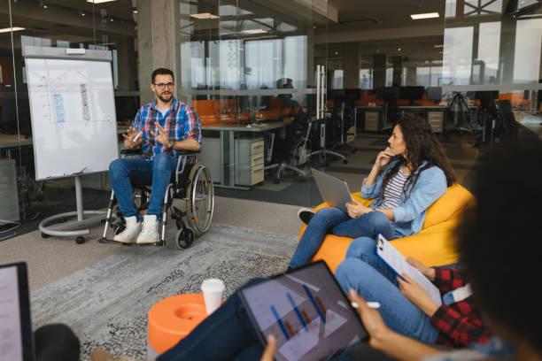 istock Programmer in a wheelchair discussing business moments in a modern office 1319935842