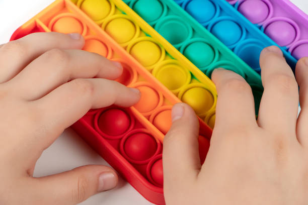 istock Child playing with rainbow pop it, pressing the bubbles with his fingers,top view. New antistress toy for children and adult. Copy space for text or design 1319936667