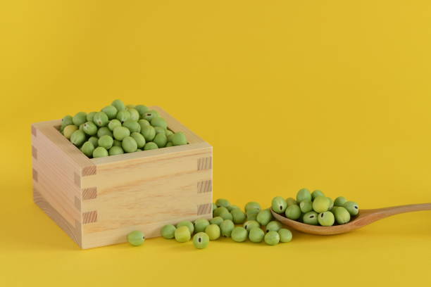 istock Fresh green peas in square wooden cup on yellow background. 1319936711
