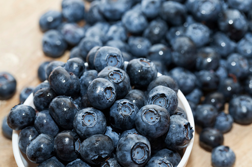 ripe juicy and tasty blueberries in large quantities on a wooden table, blueberries are harvested in season, berries can be used for eating raw or making desserts