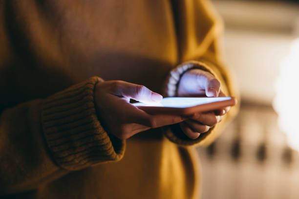mujer anónima con un suéter sosteniendo su teléfono inteligente - unrecognizable person laptop holding women fotografías e imágenes de stock