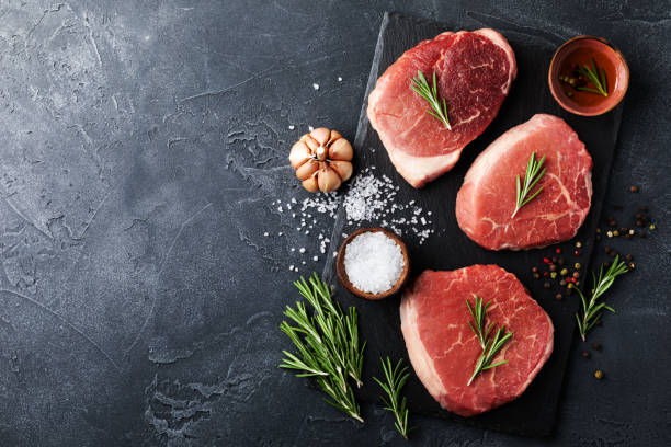 istock Raw beef meat on slate black plate. Top view and flat lay. 1319938306