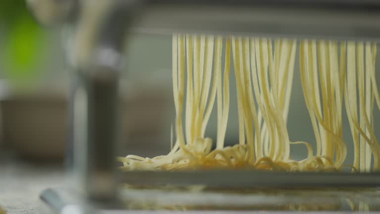 Chef using pasta making machine to make pasta from sheets of pasta