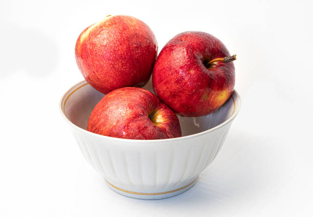 istock Red apple with drops in plate isolated on white close-up 1319939418