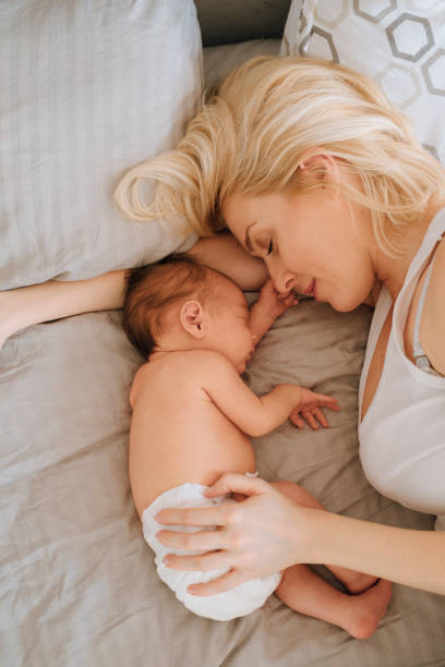 istock Bonding With Newborn: Mother Lying With Baby Girl 1319940012