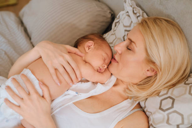 istock Bonding With Newborn: Mother Lying With Baby Girl 1319940014