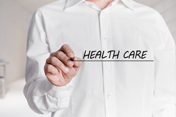 istock Man with pen underlines the words health care on virtual screen. 1319940075