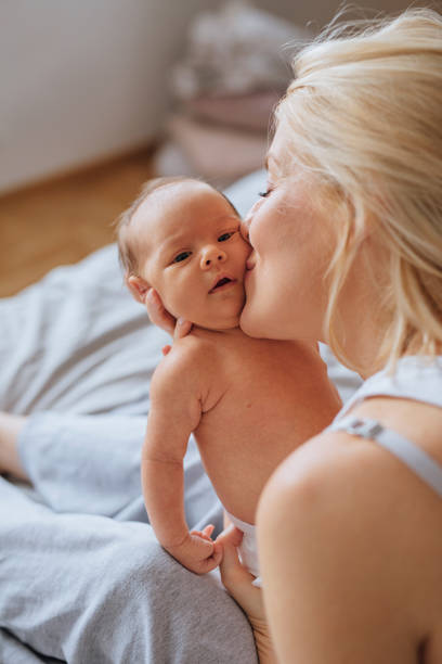 istock Bonding With Newborn: Mother Is Kissing Her Baby On Bed 1319940147