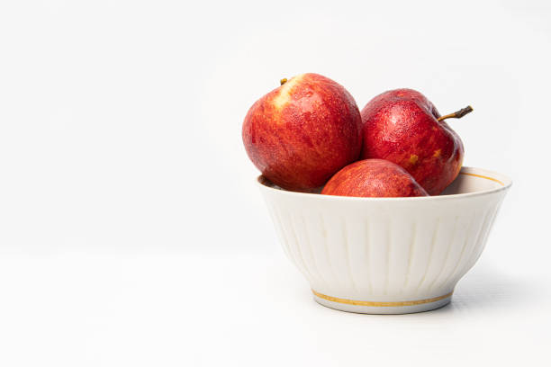 istock Red apple with drops in plate isolated on white. 1319940287