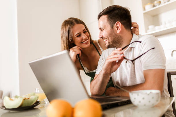istock Young couple spending time together at home in the kitchen using laptop. 1319941191