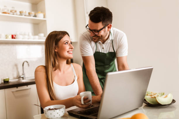 istock Young couple spending time together at home in the kitchen using laptop. 1319941263