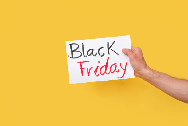 istock hand holding paper cardboard with black friday text on a yellow background isolated on a yellow background 1319942487