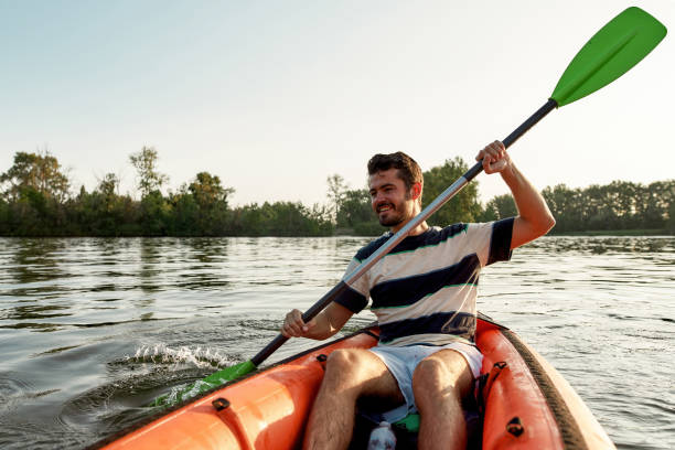 istock Happy young man smiling while kayaking in a lake, surrounded by peaceful nature on a summer afternoon 1319942554