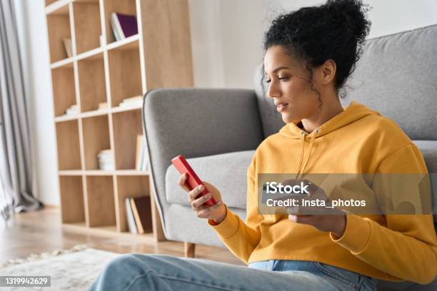 Young Adult African American Girl Sitting Indoors Doing Mobile Payment Online Stock Photo - Download Image Now