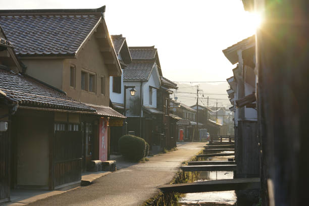 la mattina presto in una giornata di sole, il paesaggio urbano dei magazzini del muro bianco di kurayoshi (kurayoshi city uchibuki tamagawa traditional buildings preservation area) - kura river immagine foto e immagini stock