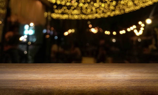 istock Empty wood table top of counter bar with abstract blurred light bokeh in dark night pub, restaurant, cafe background. Lifestyle party and celebration concept. Desk display product  with blank space. 1319947711