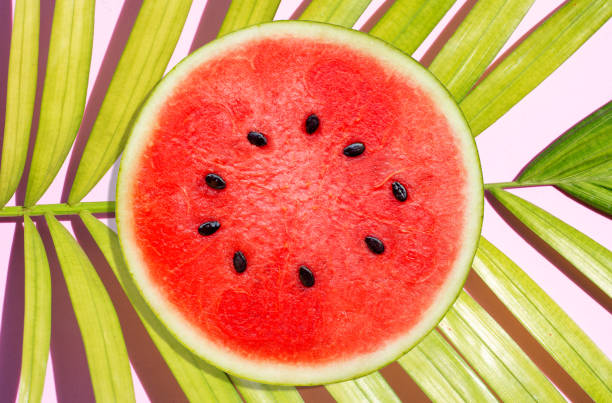 istock Watermelon on tropical palm leaves on pink surface 1319949014