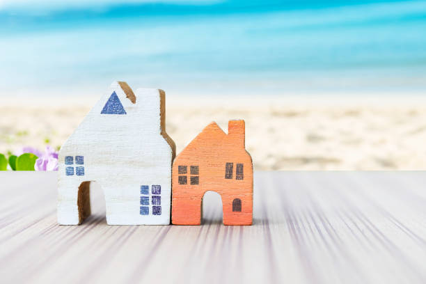 istock Wooden house model over blurred beach background 1319949176