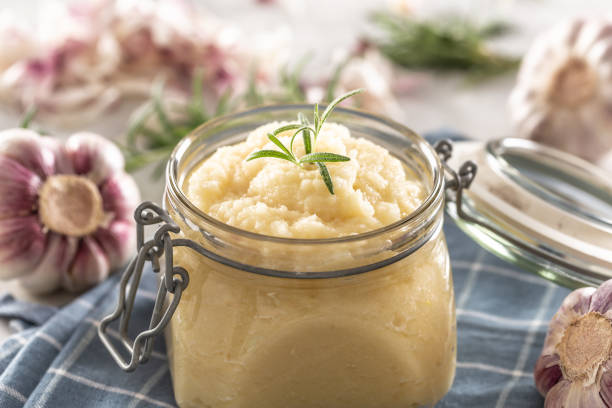 istock Aromatic garlic paste in a glass jar laid on rustic kitchen cloth with bulbs and peeled cloves and rosemary. 1319951378
