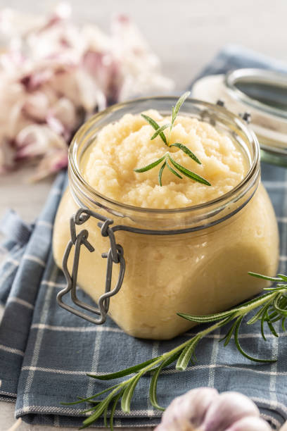istock Aromatic garlic paste in a glass jar laid on rustic kitchen cloth with bulbs and peeled cloves and rosemary. 1319951381