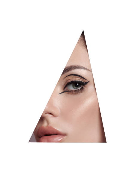 istock Beauty makeup women, eye brows eyelashes and lips in a triangular hole paper white background. Professional beauty makeup, place for text, copy space 1319951524