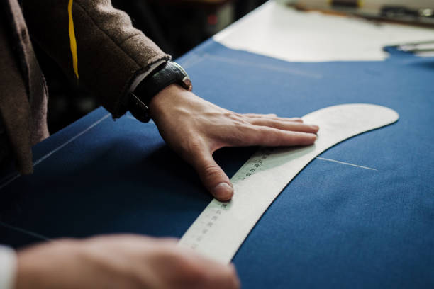 istock Tailor cutting suit fabric on sketch line 1319954184