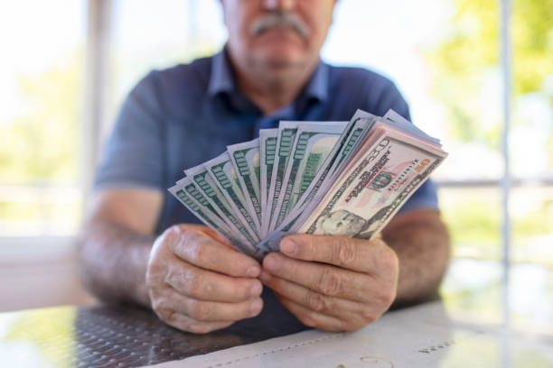 istock Mature man holding US dollars. 1319958496