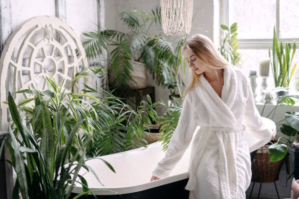 istock Young woman in bathrobe draws water into the bath 1319960178