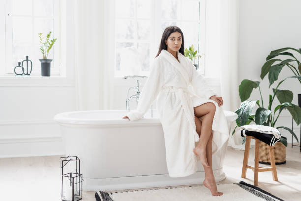 istock Young asian woman sitting on bathtub in white bathrobe 1319960370