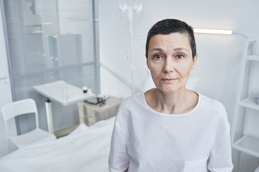 Portrait of senior patient looking at camera standing at hospital ward