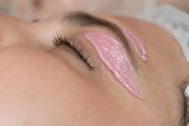Depilation and epilation female eyebrow with liquid sugar paste by spatula.
