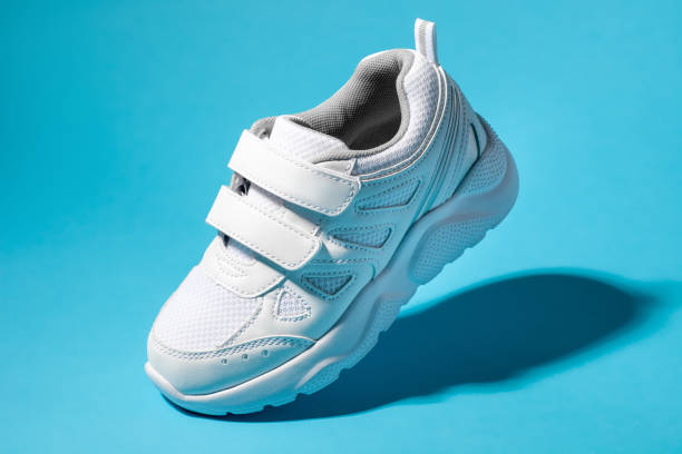 istock macro flying white child sneakers with velcro fasteners isolated on a blue background with hard light 1319967597