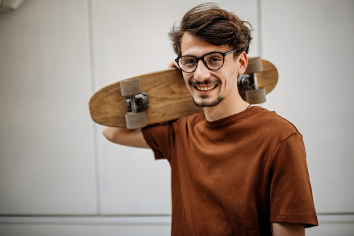 Portrait of a young  man, who is using his skateboard as a mean of transportation all over the city