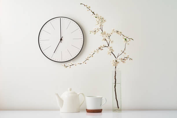 istock Wall clock, blooming branch and cup on white background 1319968575