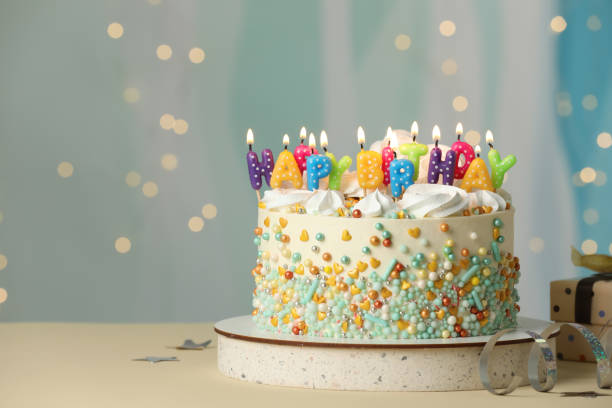 istock Beautiful birthday cake with burning candles and decor on white table. Space for text 1319969071