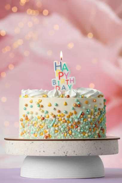 istock Beautiful birthday cake with burning candle on violet table 1319969088