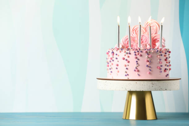 istock Beautifully decorated birthday cake on turquoise wooden table, space for text 1319969150