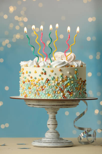 istock Beautiful birthday cake with burning candles and decor on white table 1319969154