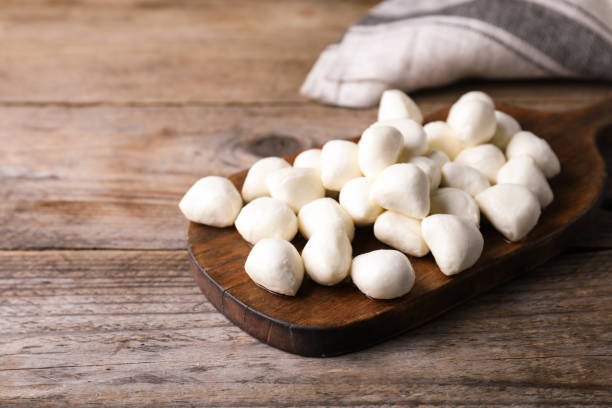 istock Board with delicious mozzarella cheese balls on wooden table. Space for text 1319969989