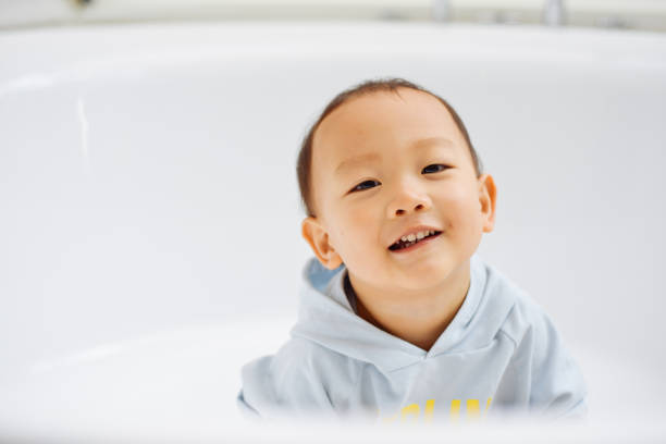 Baby boy having fun playing with a toy crocodile while taking a bath