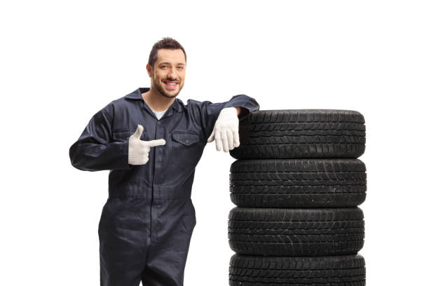 istock Auto mechanic leaning on a pile of tires and pointing 1319972607