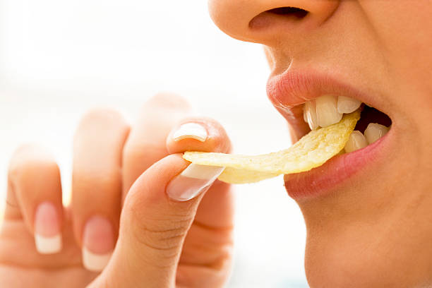 Woman biting potato chips Close-up of a woman biting potato chips, selective focus, canon 1Ds mark III human mouth stock pictures, royalty-free photos & images