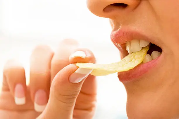 Close-up of a woman biting potato chips, selective focus, canon 1Ds mark III