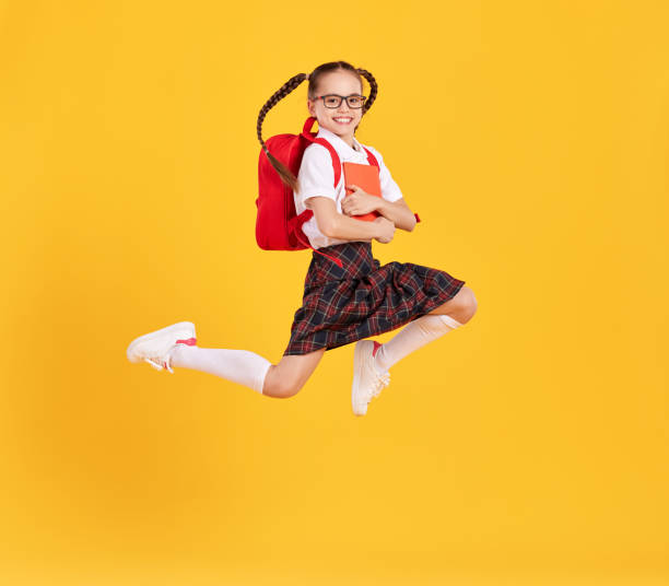 istock Excited schoolgirl jumping high in studio 1319973799