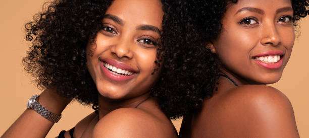 istock Two beautiful afro women posing together smiling, looking at camera. 1319973829