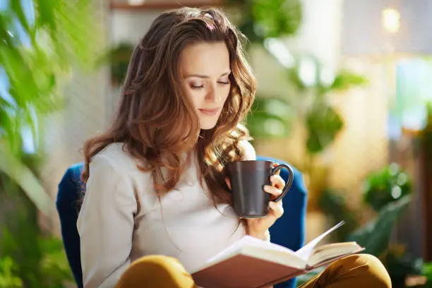 Photo of stylish female with long wavy hair in house in sunny day