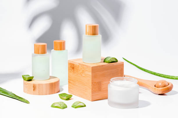 naturkosmetik mit aloe auf holzpodesten in mehrwegflaschen mit pflanzenschatten auf dem hintergrund - scincare stock-fotos und bilder