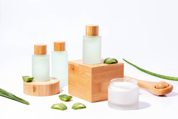 cosméticos à base de plantas naturais com aloe em pódios de madeira em garrafas reutilizáveis com sombra de planta no fundo - scincare - fotografias e filmes do acervo