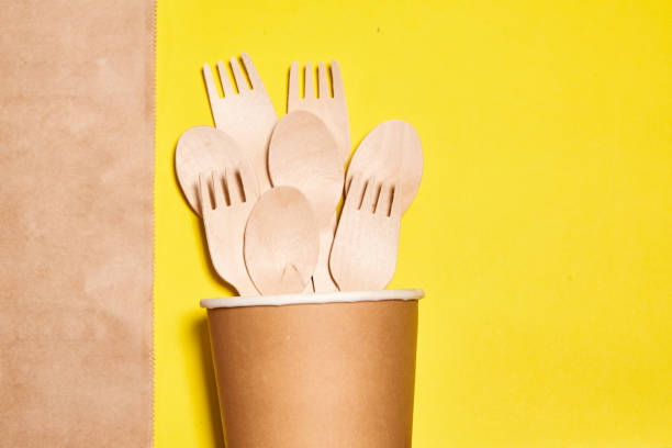 istock Eco friendly disposable kitchenware utensils. Wooden forks and spoons in paper cup. ecology, zero waste concept. copyspace. Layout of wooden disposable teaspoons 1319977906