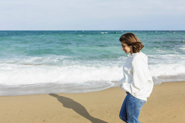 Young relaxed woman enjoying and walking alone on the beach - Copy space on the left side